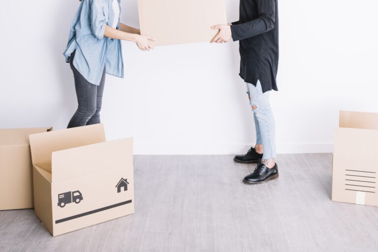 Cropped image of a couple surrounded by moving boxes on the floor in the concept of 'Differences Between Man and Van Services and Traditional Removals'.