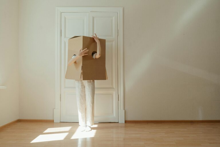 A woman hiding herself in a box in the concept of 'What Are the Hidden Costs in Home Removals Services'