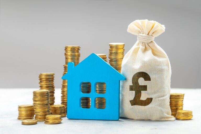 Miniature house with stacks of coins and money bag with British Pound sign in the concept of 'What Factors Influence the Cost of a Man and Van Service'.
