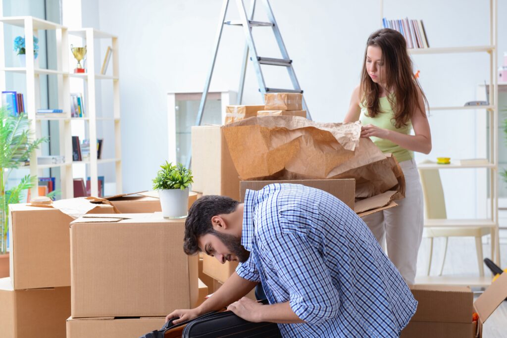 Young couple is unpacking after the house move in the concept of packing materials disposal